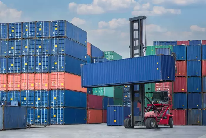 A forklift carrying a shipping container.