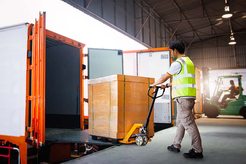 A worker loading a container on a truck with a forklift.