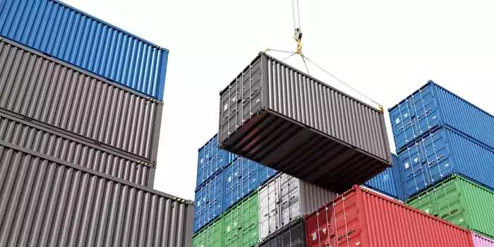 A shipping container being raised by a crane.